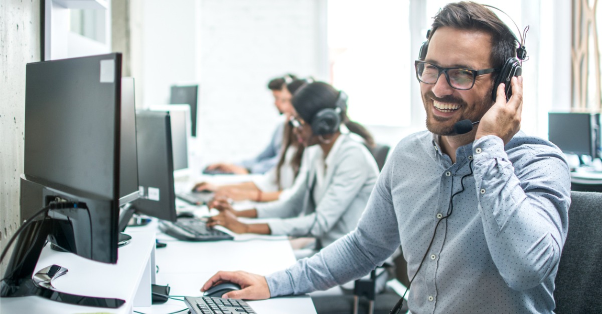 Photo showing a man smiling while working, having a great employee experience in a contact center.