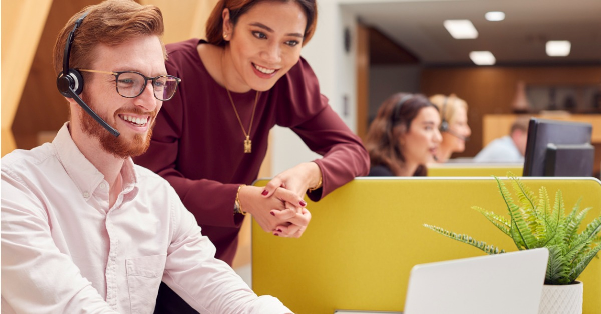 Image showing a contact center manager working alongside a contact center employee. Both are working to improve customer experience and customer engagement.