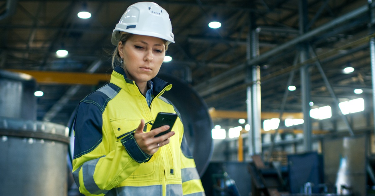 A utility worker checks her phone as she deals with a utility service disruption.