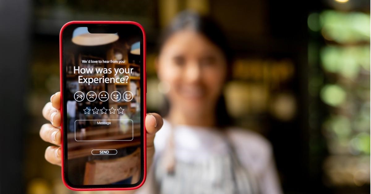 Photo of a woman holding up a phone with on-screen text saying 