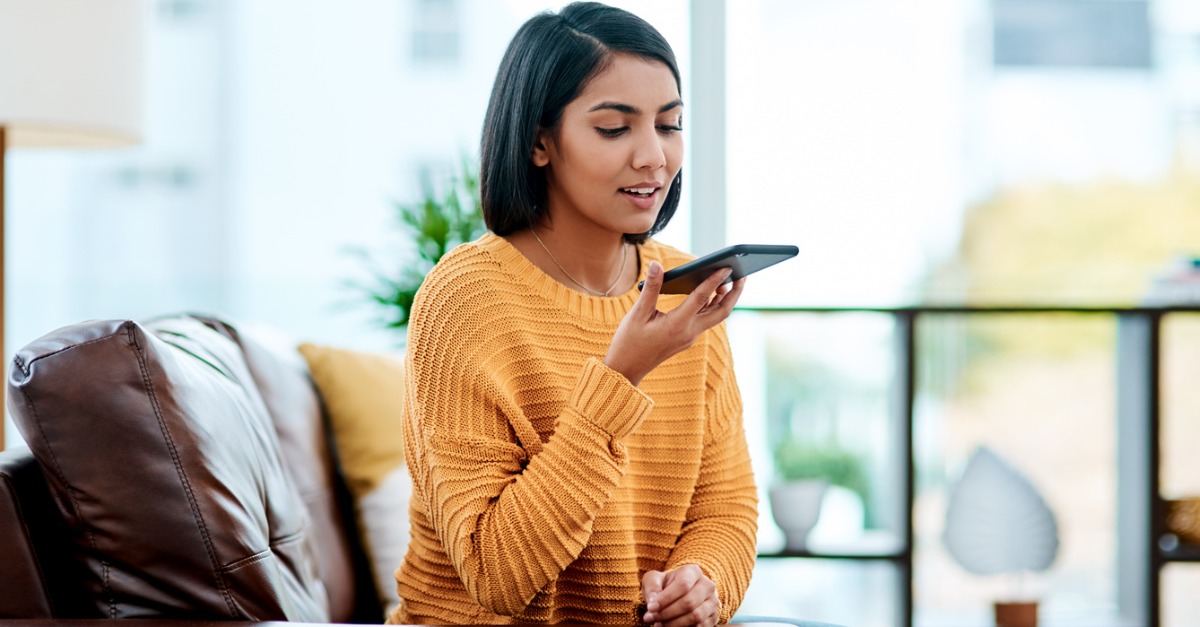 Photo of a woman talking to some form of voice technology on her smartphone.